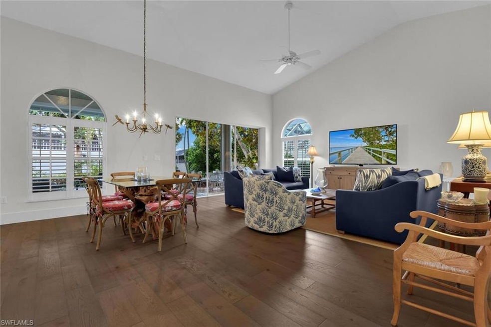 Dining area featuring dark wood-type flooring, ceiling fan, a chandelier, and high vaulted ceiling