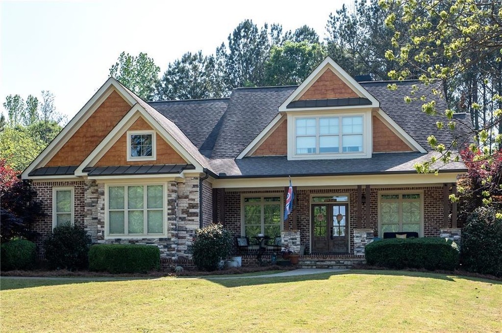 Craftsman-style house featuring a front lawn, a porch, a shingled roof, and stone siding