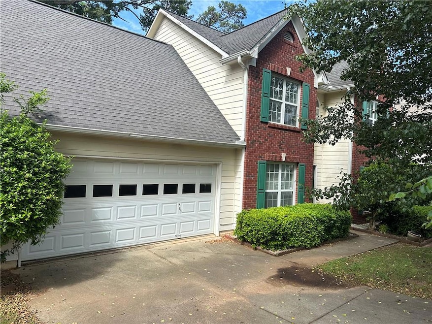 View of property exterior with driveway, brick siding, roof with shingles, and an attached garage