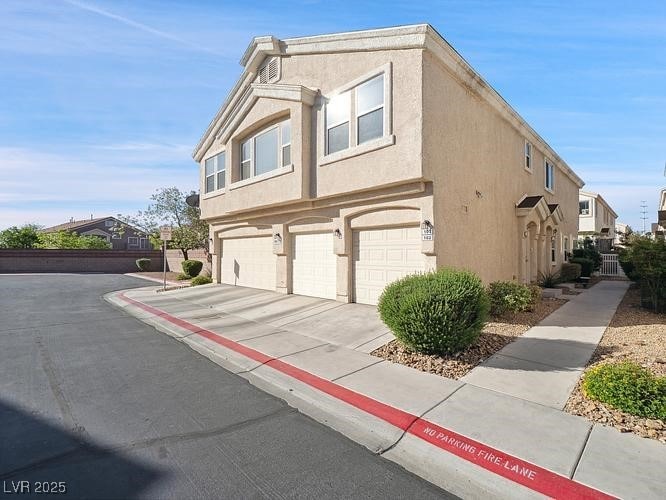 View of side of home featuring driveway, stucco si