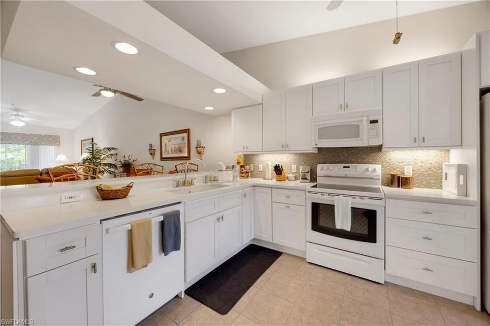 Kitchen with a peninsula, ceiling fan, white appliances, lofted ceiling, and tasteful backsplash
