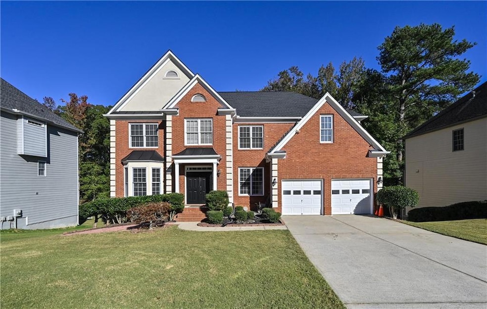 View of front of home with brick siding, driveway, a garage, and a front lawn