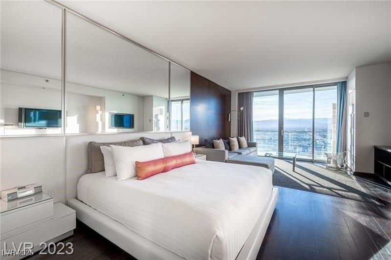 Bedroom featuring a wall of windows and dark wood