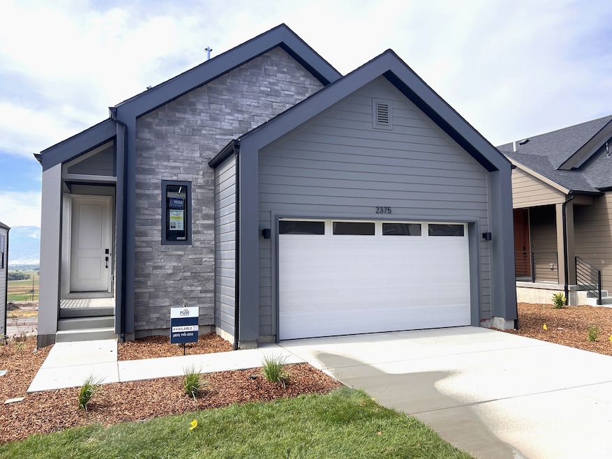 View of front facade featuring stone siding, an attached garage, and concrete driveway