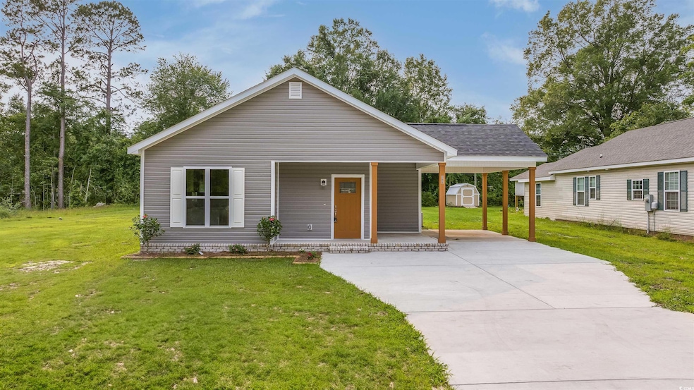 View of front of house with a porch, driveway, a front lawn, and a carport