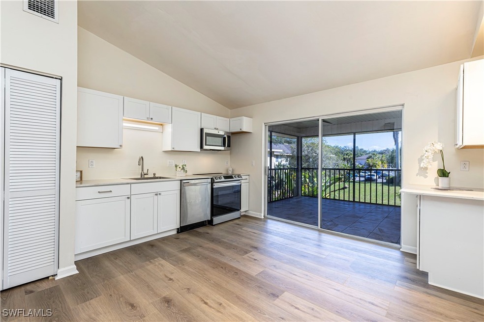 Kitchen with white cabinetry, appliances with stai