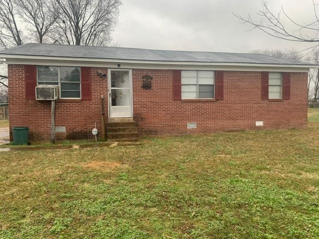 View of front facade with a front lawn, entry steps, cooling unit, crawl space, and brick siding