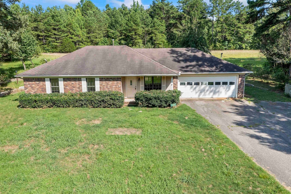 Ranch-style home with asphalt driveway, an attached garage, a front yard, and a shingled roof