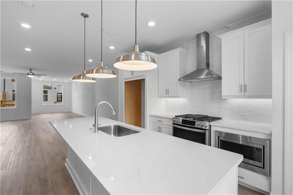 Welcome Home to Homesite #194 at Millcroft! Kitchen features quartz countertops, built in microwave, single bowl sink, pendent lights, chimney hood and tile backsplash