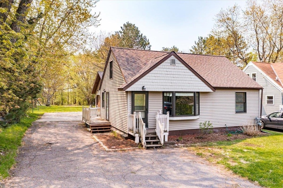 View of front of house featuring driveway and roof with shingles