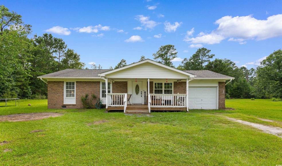 Ranch-style home with a porch, brick siding, an attached garage, a front yard, and driveway