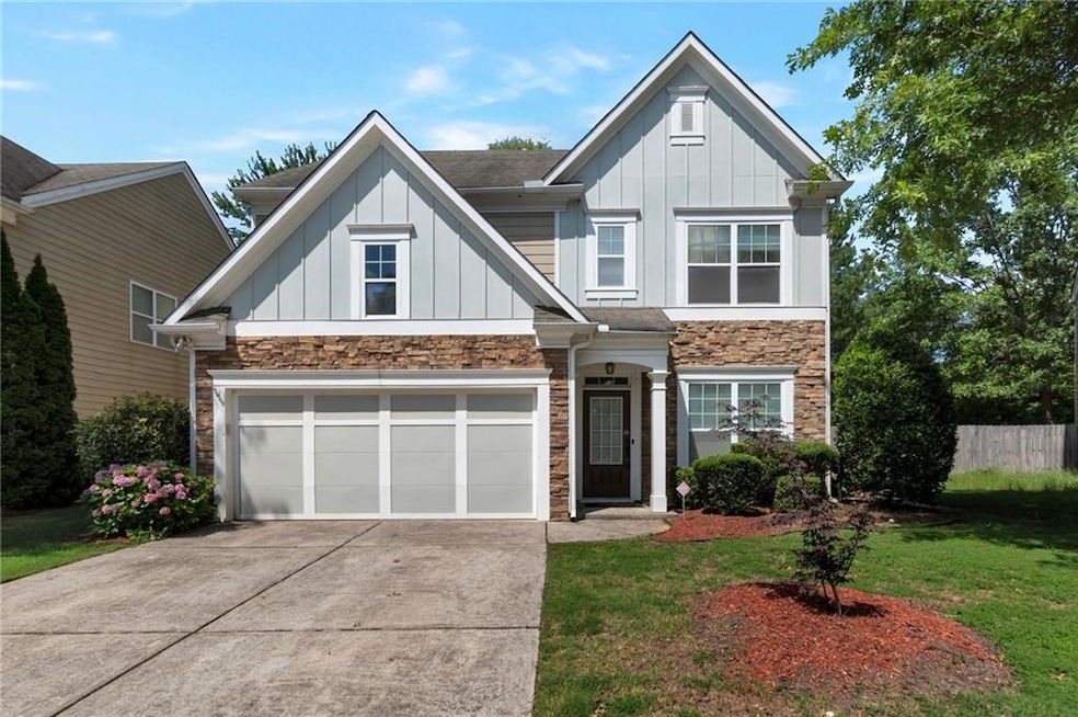 View of front of house with board and batten siding, stone siding, driveway, and a garage