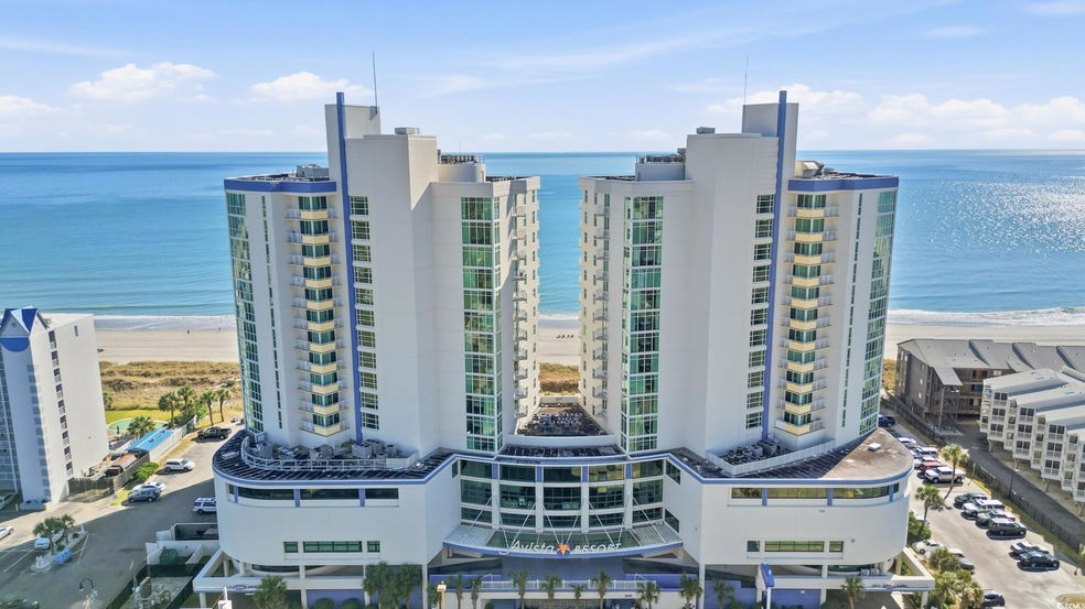 View of apartment building / complex featuring view of water and beach