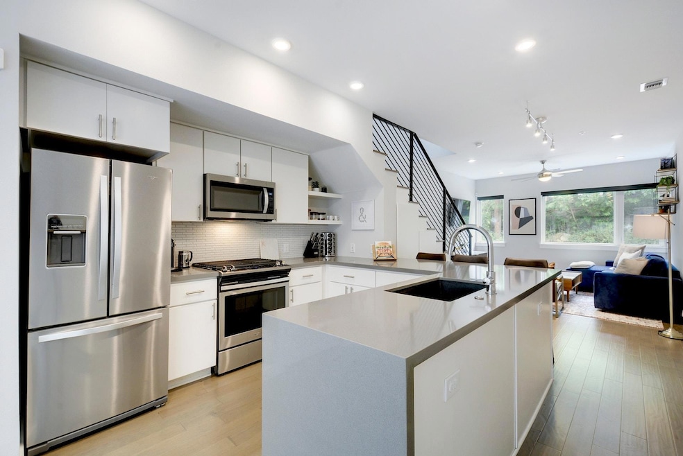Kitchen with white cabinets, appliances with stai