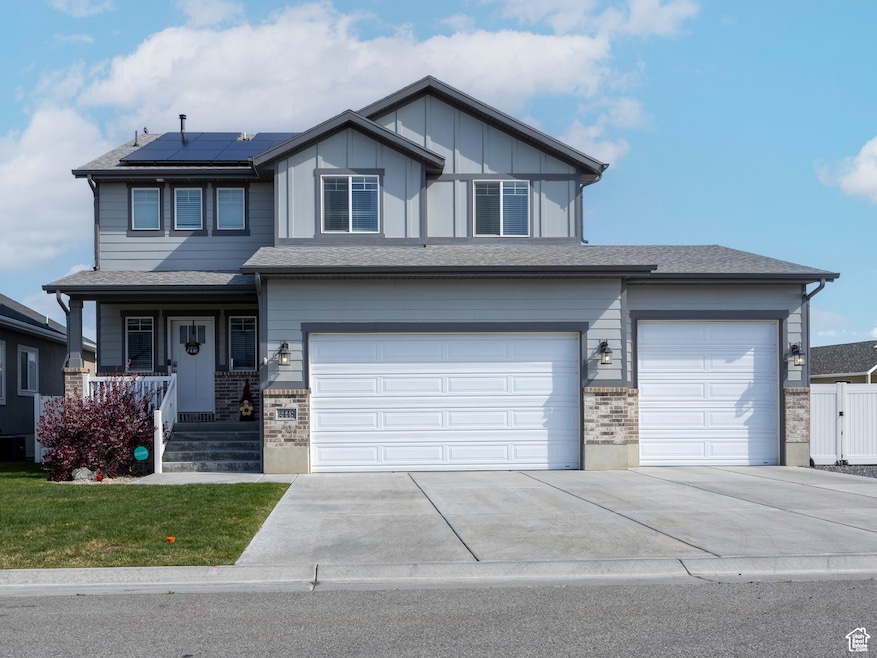 View of front of property with driveway, covered porch, roof mounted solar panels, an attached garage, and brick siding