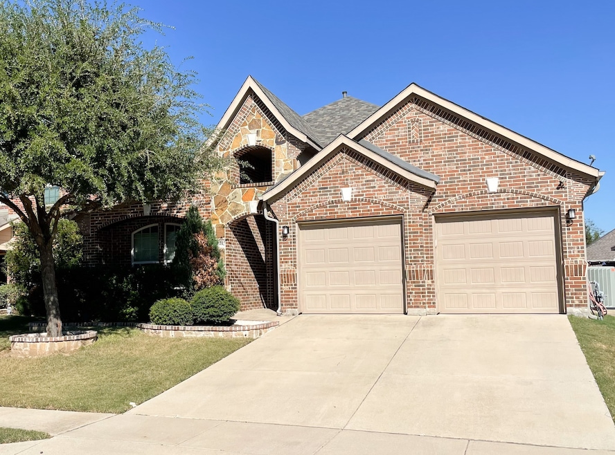 Brick and stone single story home with driveway, an attached garage, landscaped front yard