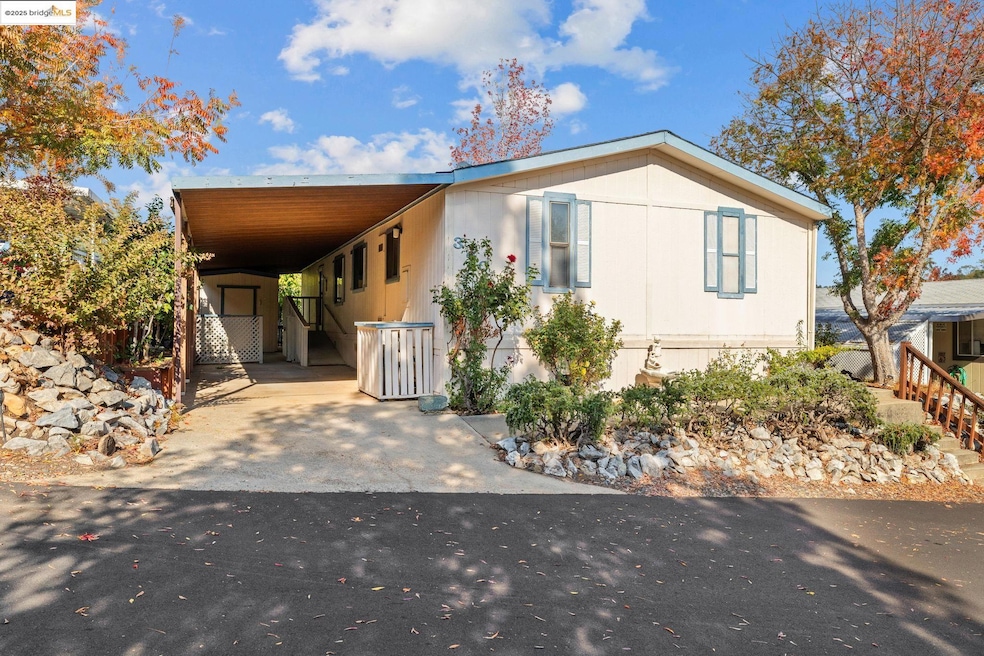 Manufactured / mobile home featuring concrete driveway and a carport