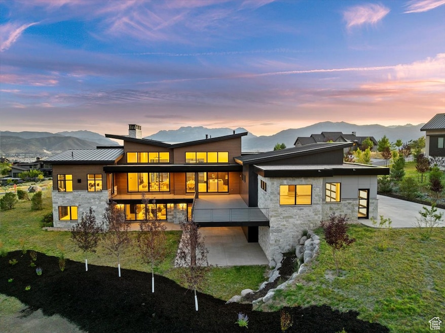 Back of property at dusk with stone siding, a mountain view, a chimney, and a standing seam roof