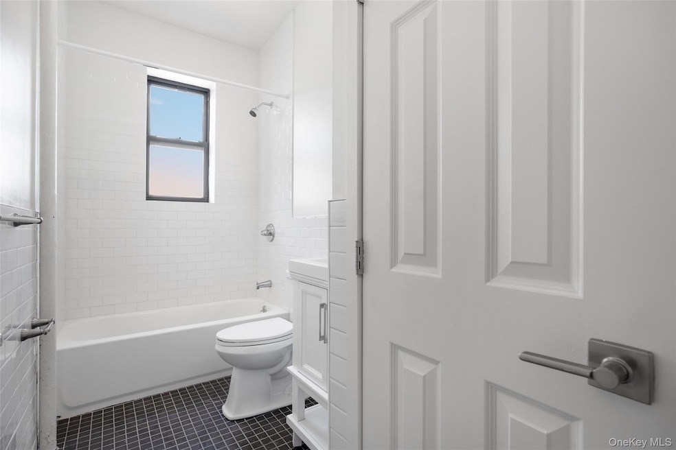 Bathroom featuring vanity, bathtub / shower combination, and dark tile patterned flooring