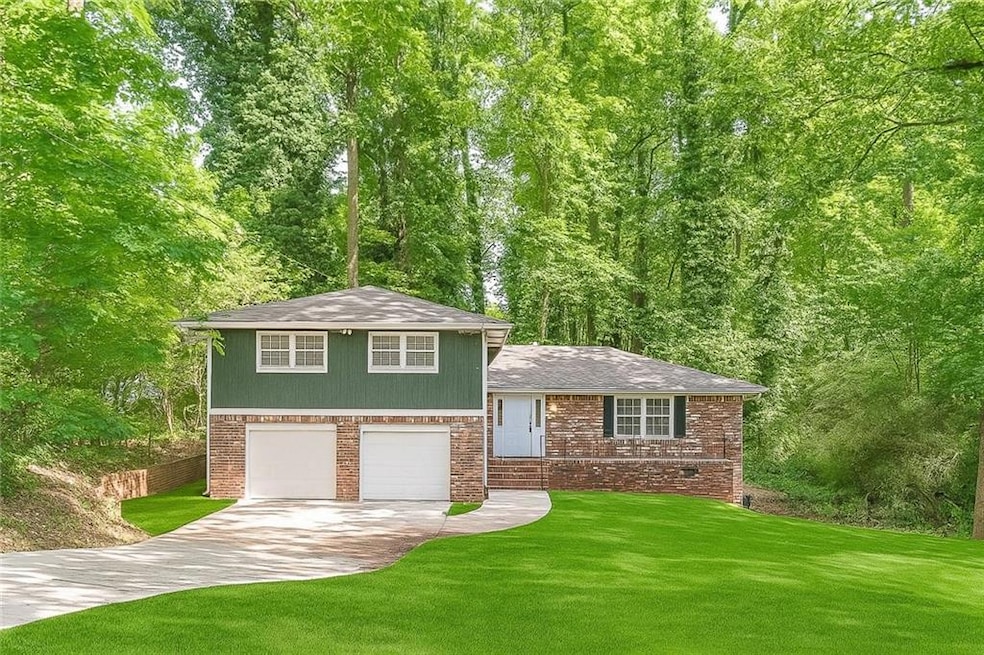 Split level home with concrete driveway, a shingled roof, a front lawn, brick siding, and an attached garage