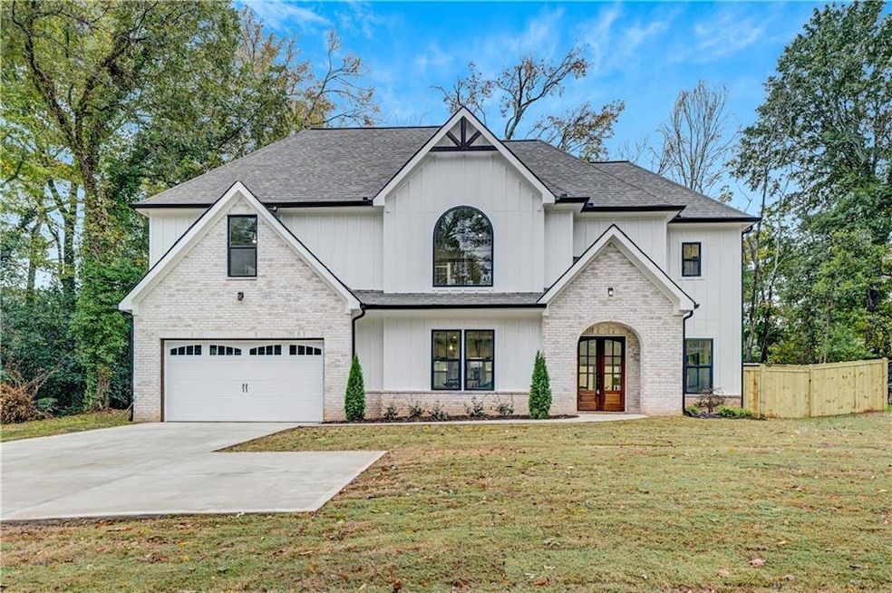 View of front of property featuring driveway, roof with shingles, french doors, a garage, and brick siding