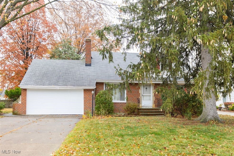 View of Cape Cod house featuring a chimney, driveway, a front yard, brick siding, and a garage