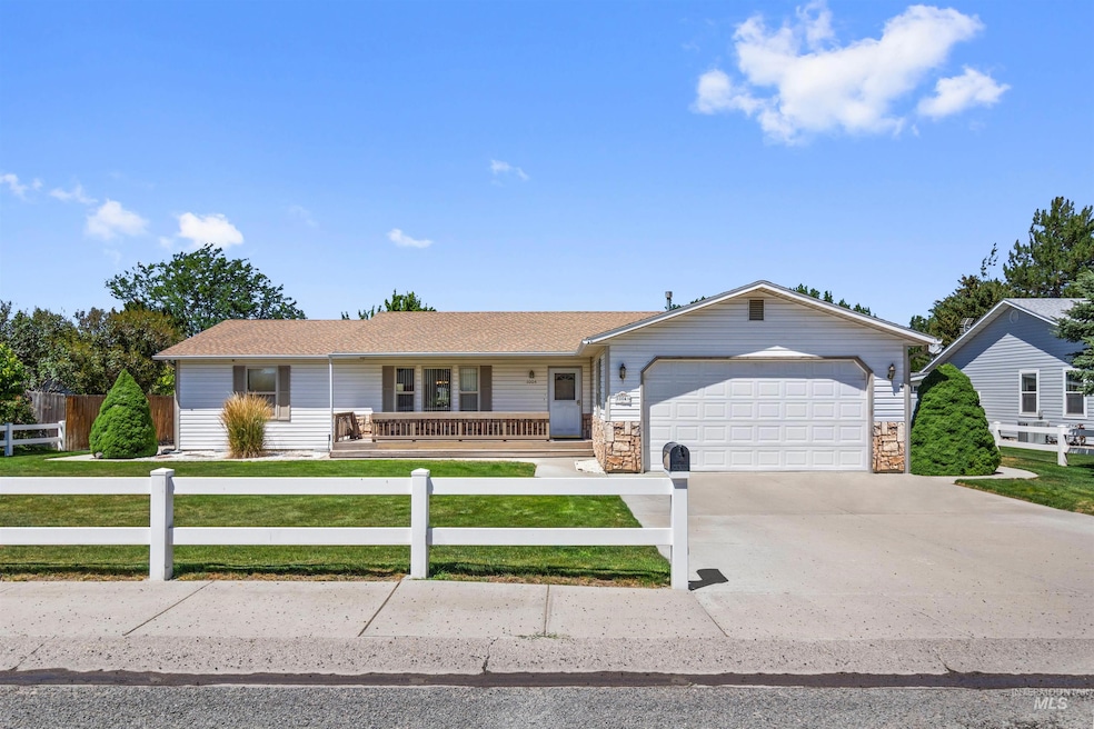 Ranch-style home featuring driveway, a porch, a fenced front yard, an attached garage, and stone siding
