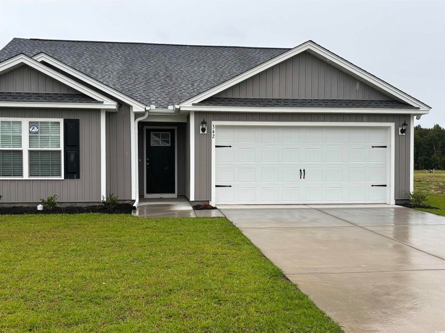 Ranch-style home featuring roof with shingles, a garage, driveway, and a front yard