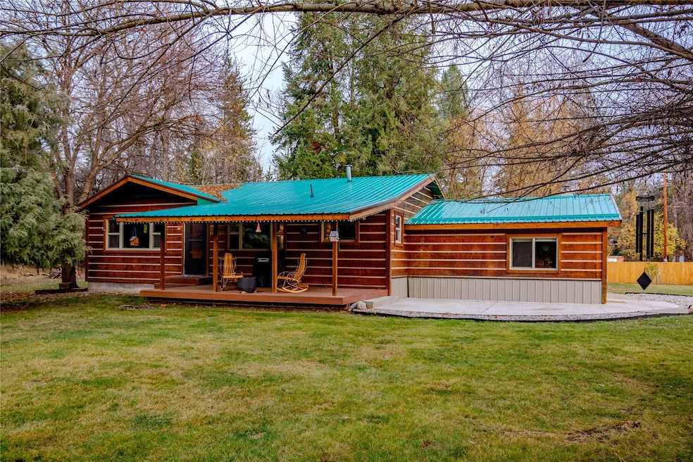 Rear view of house featuring a yard, a wooden deck, and a metal roof