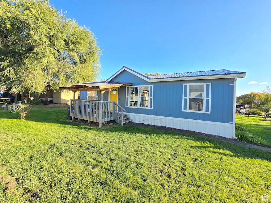 Manufactured / mobile home featuring a front lawn, a metal roof, and a wooden deck