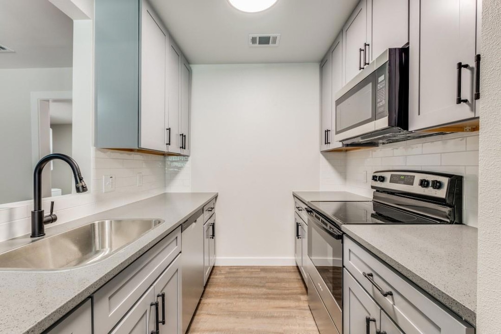 Kitchen with light stone countertops, sink, stainl