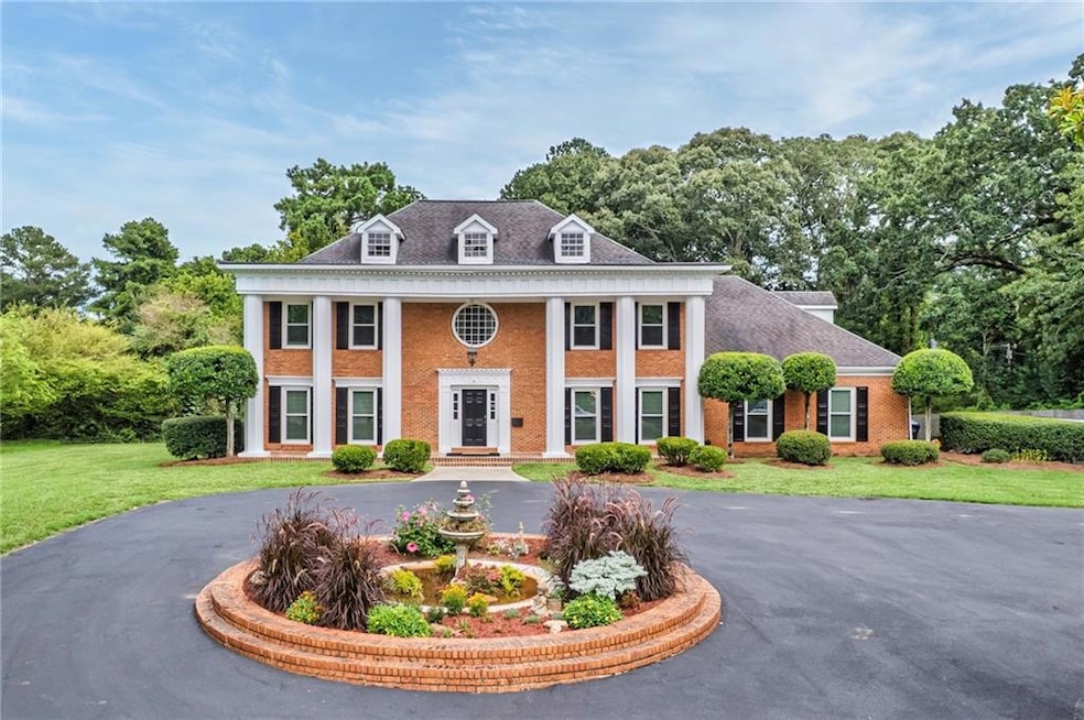 Greek revival inspired property with covered porch, brick siding, and a front yard