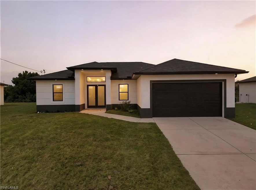 Prairie-style house featuring a yard, driveway, a garage, and stucco siding