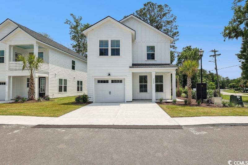 Modern inspired farmhouse with board and batten siding, driveway, an attached garage, and a front yard