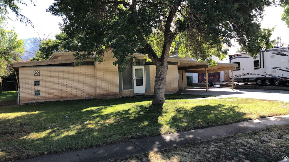 View of front of home with brick siding, crawl space, a carport, and a front yard