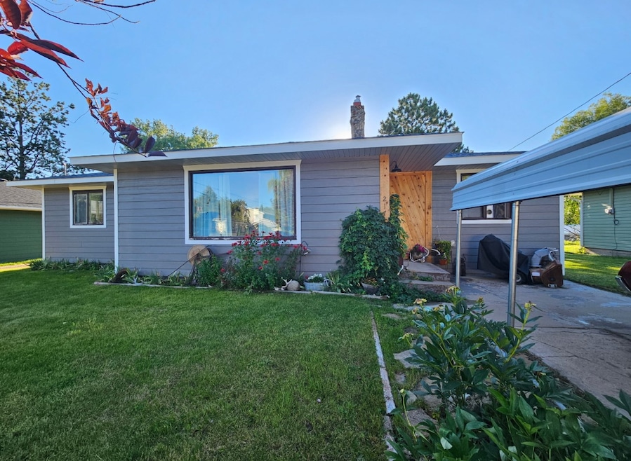 View of front of property featuring a front yard, a chimney, and a carport