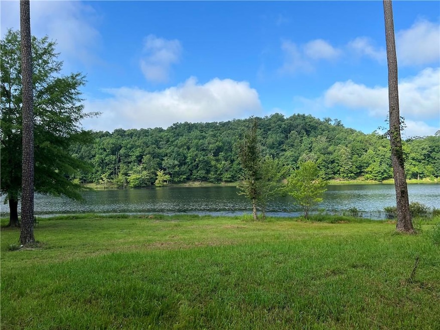 View of grassy yard featuring a water view and a wooded view