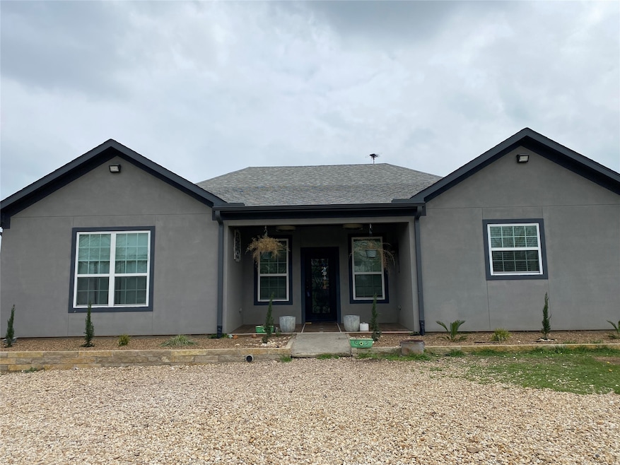 Ranch-style home featuring a porch, stucco siding, and roof with shingles