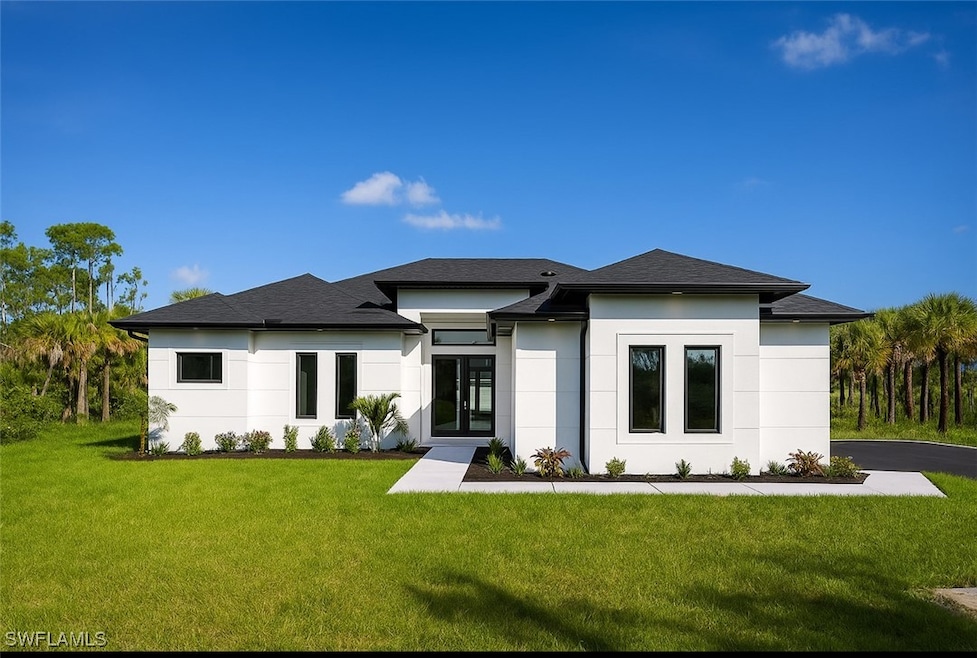 Back of property with stucco siding, a lawn, and a