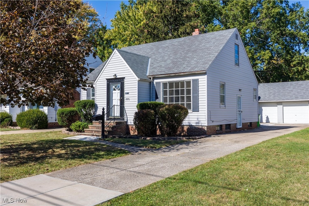 View of front facade with an outbuilding, a front yard, a chimney, a garage, and roof with shingles