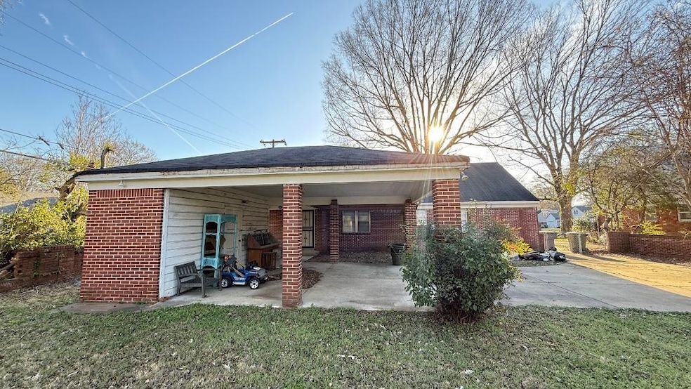 Rear view of house featuring a yard, brick siding, and fence