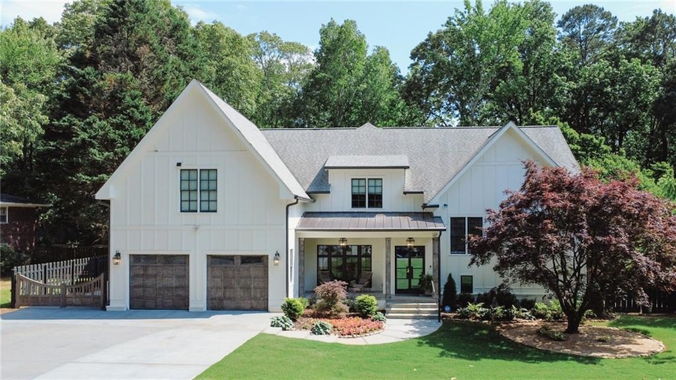 Modern farmhouse with board and batten siding, a standing seam roof, driveway, and roof with shingles