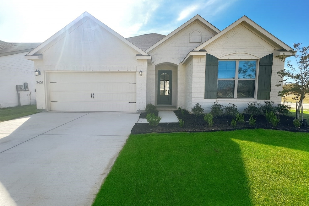 Ranch-style home featuring a front yard, concrete driveway, brick siding, and a garage