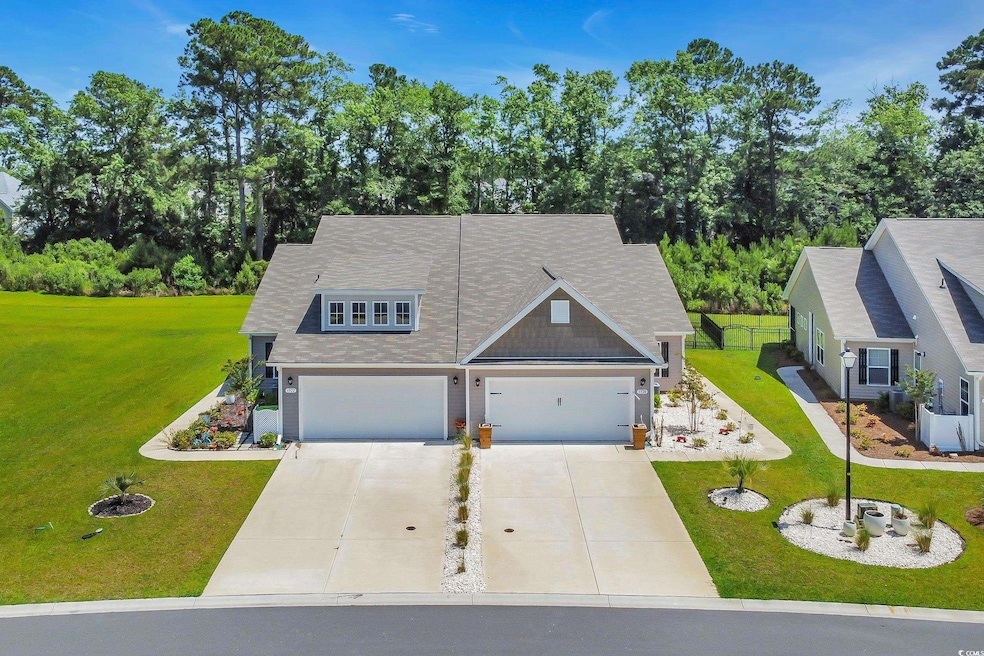View of front facade featuring concrete driveway, a garage, view of wooded area, and a shingled roof