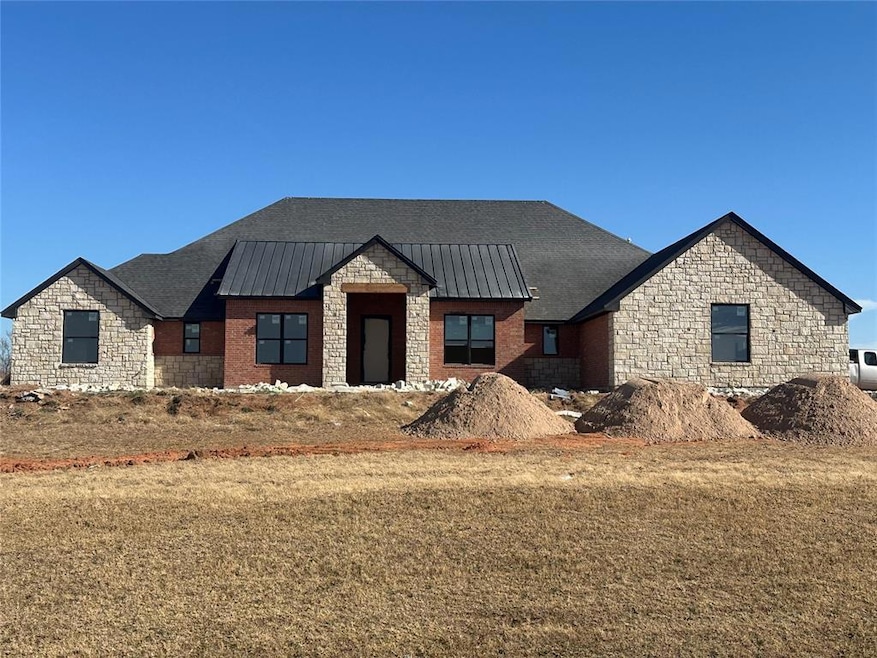 View of front of house featuring stone siding, a standing seam roof, a metal roof, and a front yard