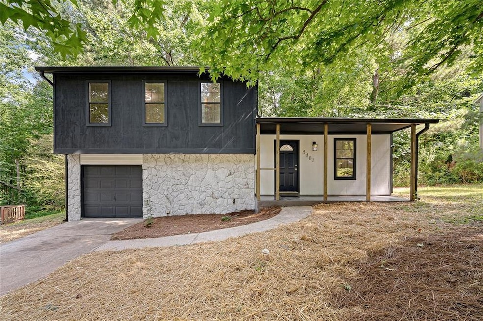 Split level home with an attached garage, asphalt driveway, and stone siding