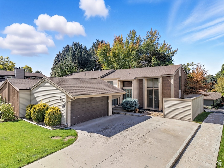 Mid-century inspired home featuring roof with shingles, concrete driveway, a front lawn, and brick siding