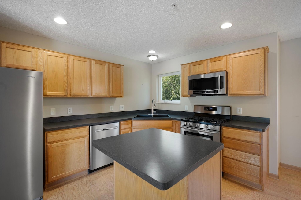 Kitchen features stainless steel appliances, center island and kitchen window overlooking the backyard green space.