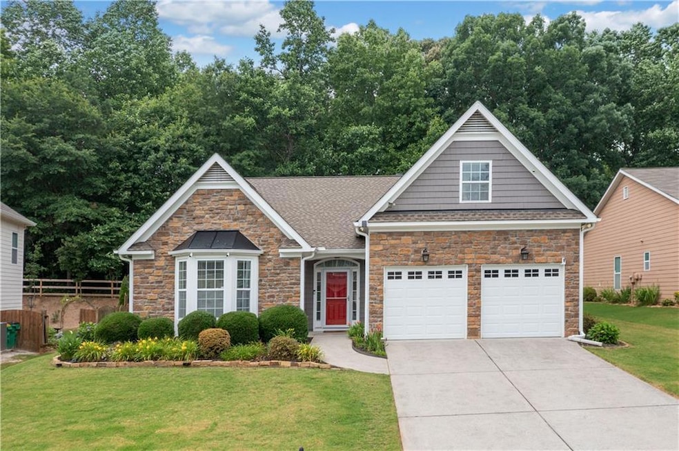 View of front of house featuring stone siding, concrete driveway, and a shingled roof