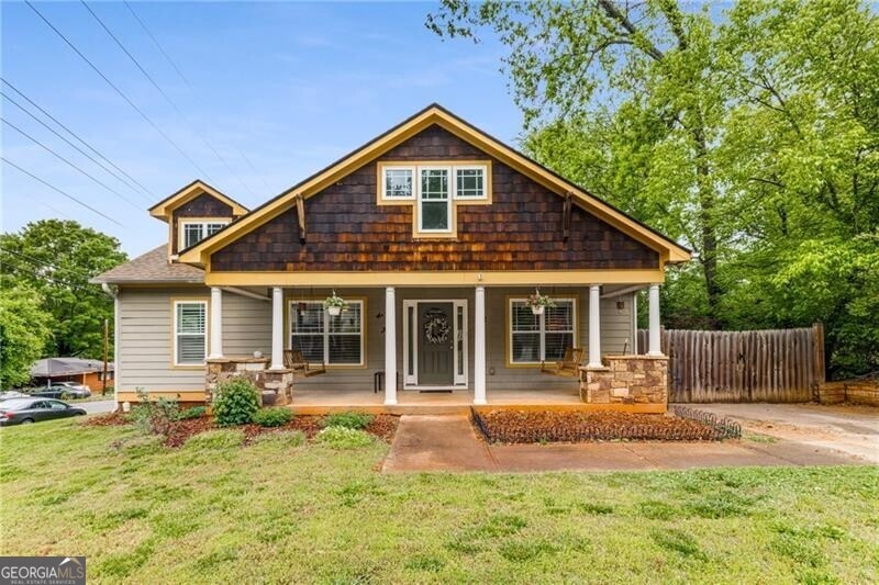 Bungalow-style home featuring a front yard, covered porch, and fence